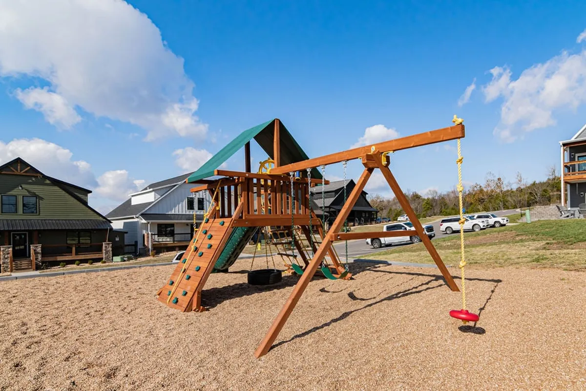 A colorful playground structure and swing set surrounded by neighboring houses, with children actively playing and families gathered nearby. The scene evokes joyful moments and safe, community-oriented family fun.